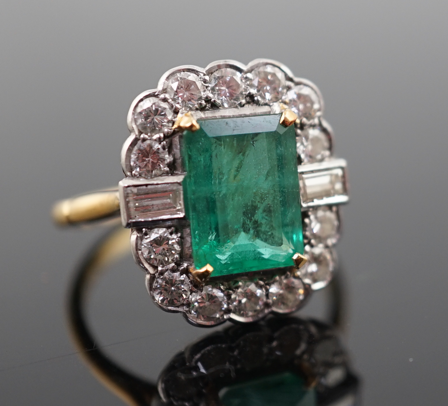 An Art Deco style gold, emerald and diamond set oval cluster ring